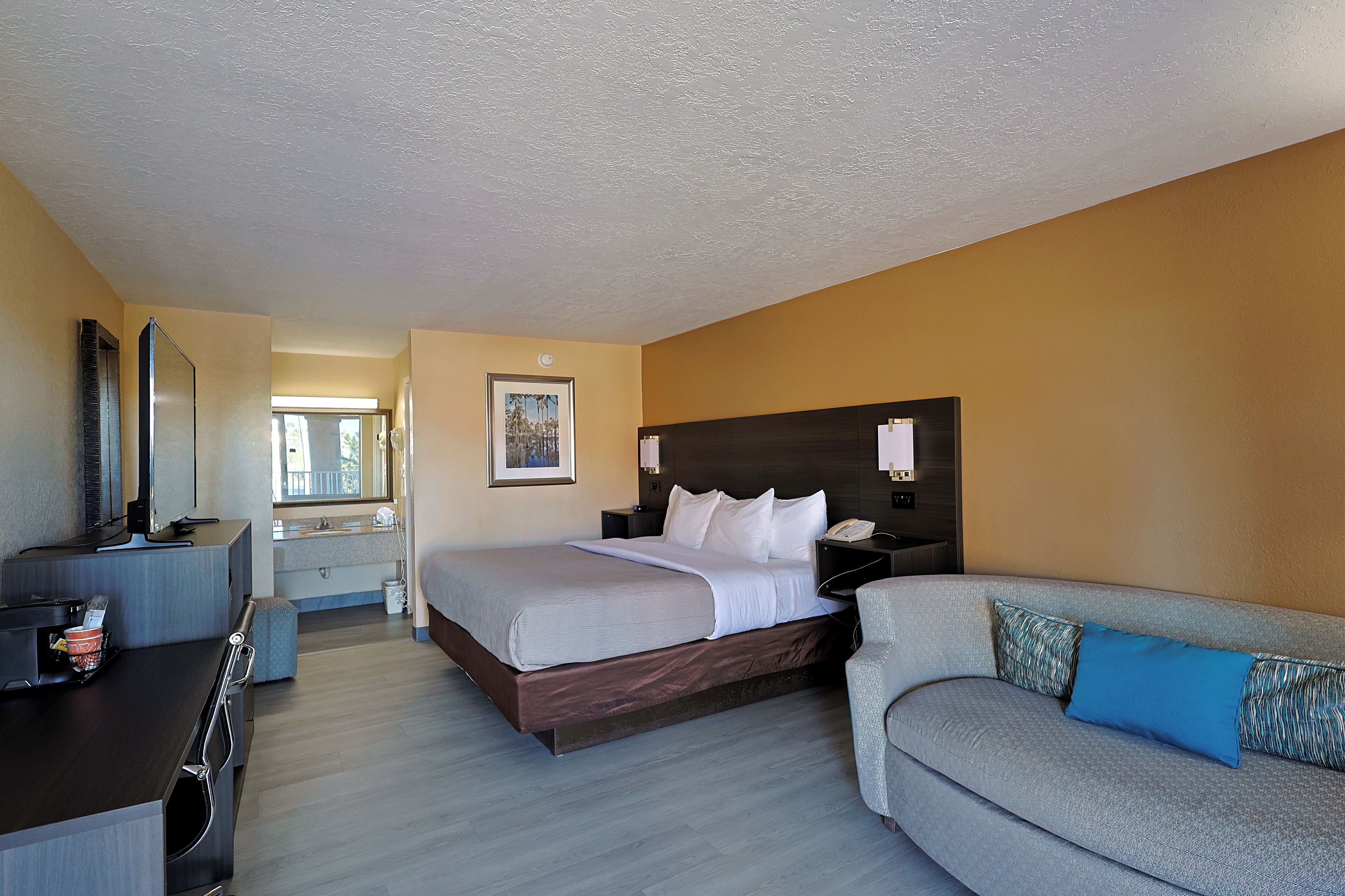 Una habitación de hotel con cama, escritorio, sofá, baño y ventana.