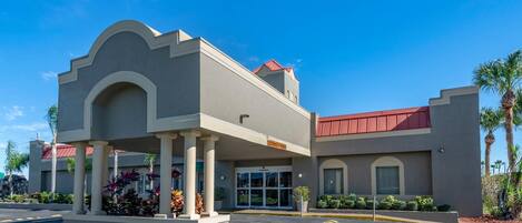 A hotel with a two-story structure, a covered entrance, and a parking lot with marked spaces.