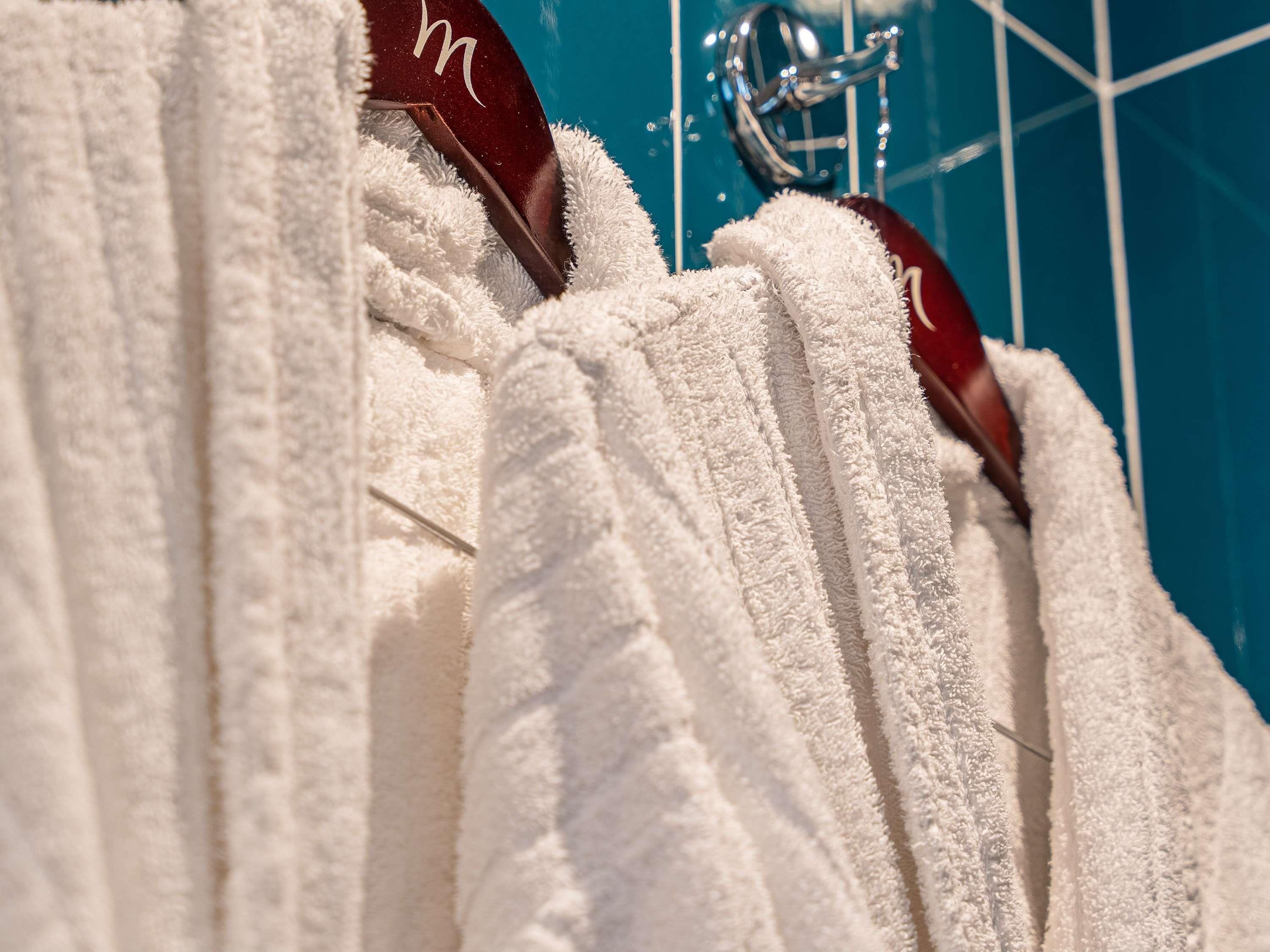 A row of white towels hanging on a rack with a metal hook.