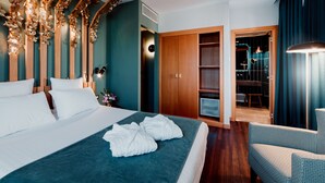 A modern hotel room with a large bed, wooden wardrobe, and a seating area.