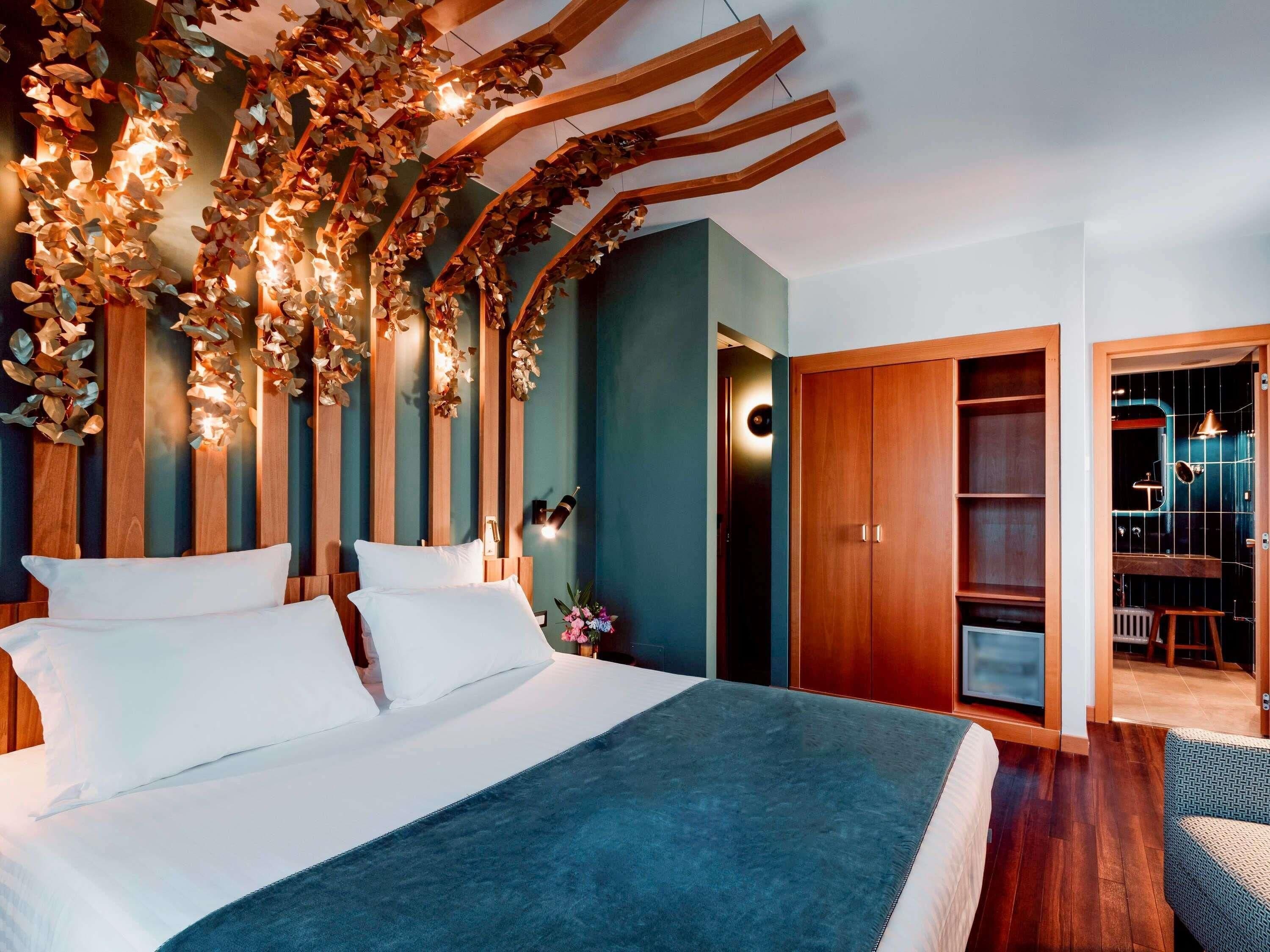 Une chambre à coucher avec un lit, des éléments de décoration murale en bois, une armoire et une salle de bain visible à travers une porte ouverte.