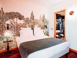 A bedroom with a bed, a nightstand, a mirror, and a door leading to a bathroom.