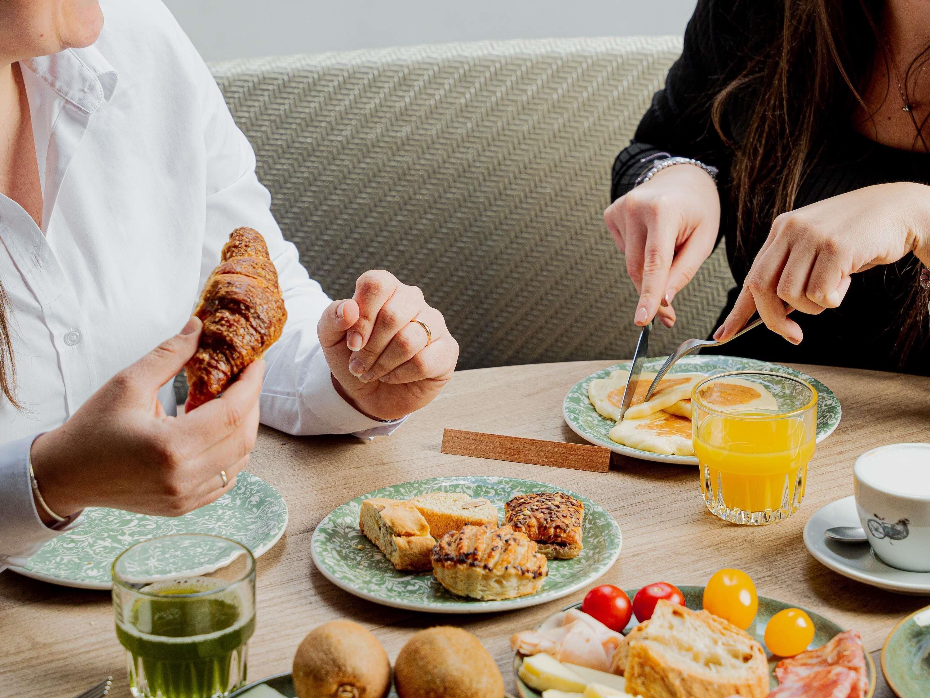 A dining table with plates of food, a glass of juice, and a cup of coffee.