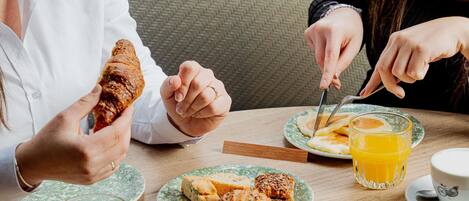 A dining table with plates of food, a glass of juice, and a cup of coffee.
