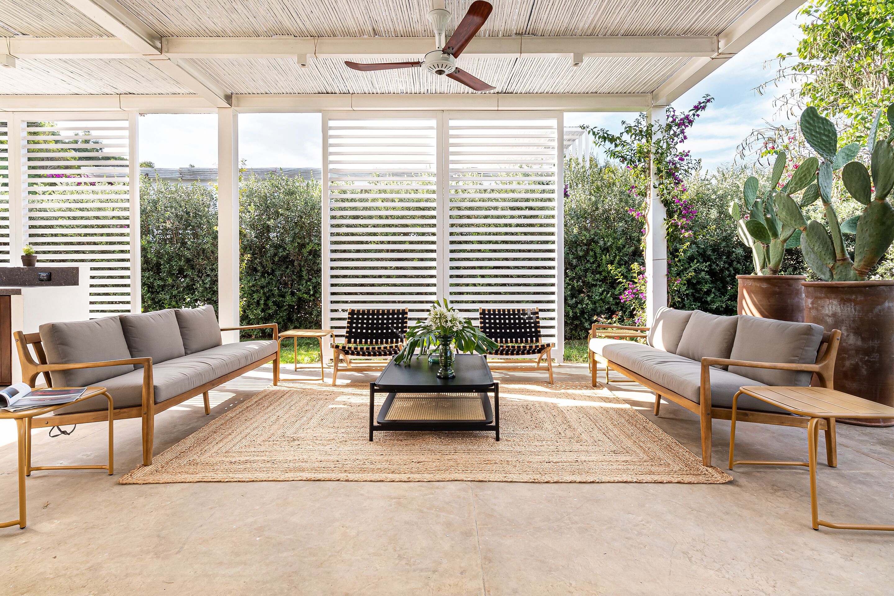 A covered patio with a sofa, armchairs, a coffee table, and a ceiling fan.