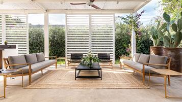 A covered patio with a sofa, armchairs, a coffee table, and a ceiling fan.