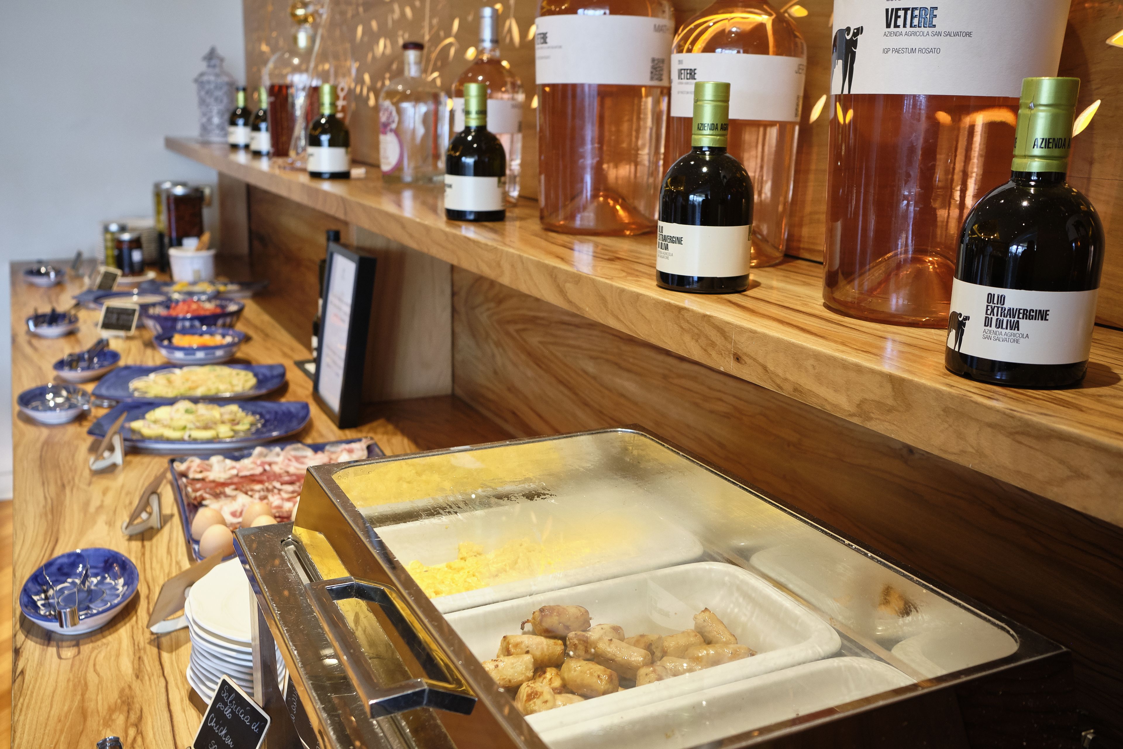 A buffet with various food items and wine bottles on display.