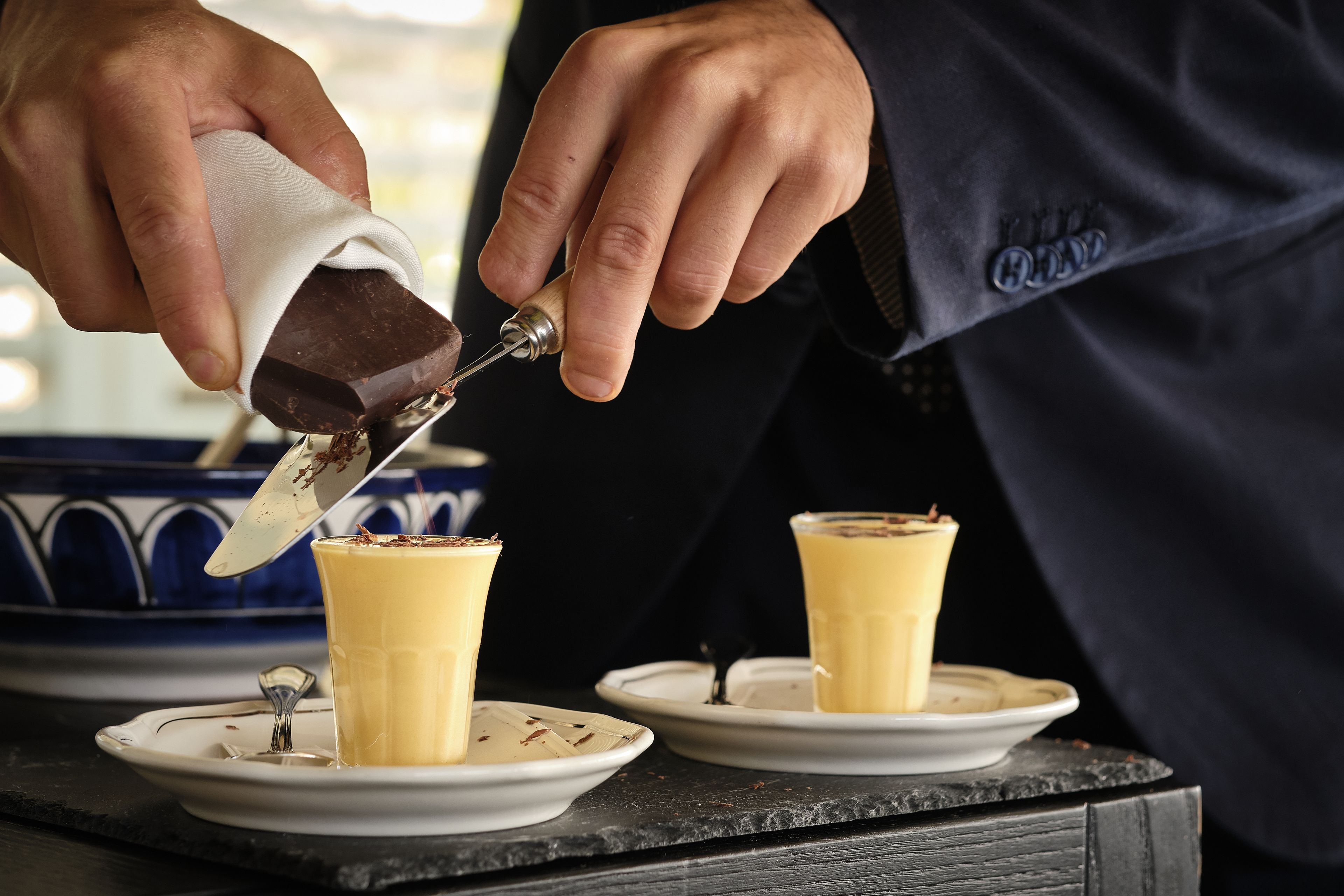 Alguém despejando calda de chocolate sobre uma sobremesa.