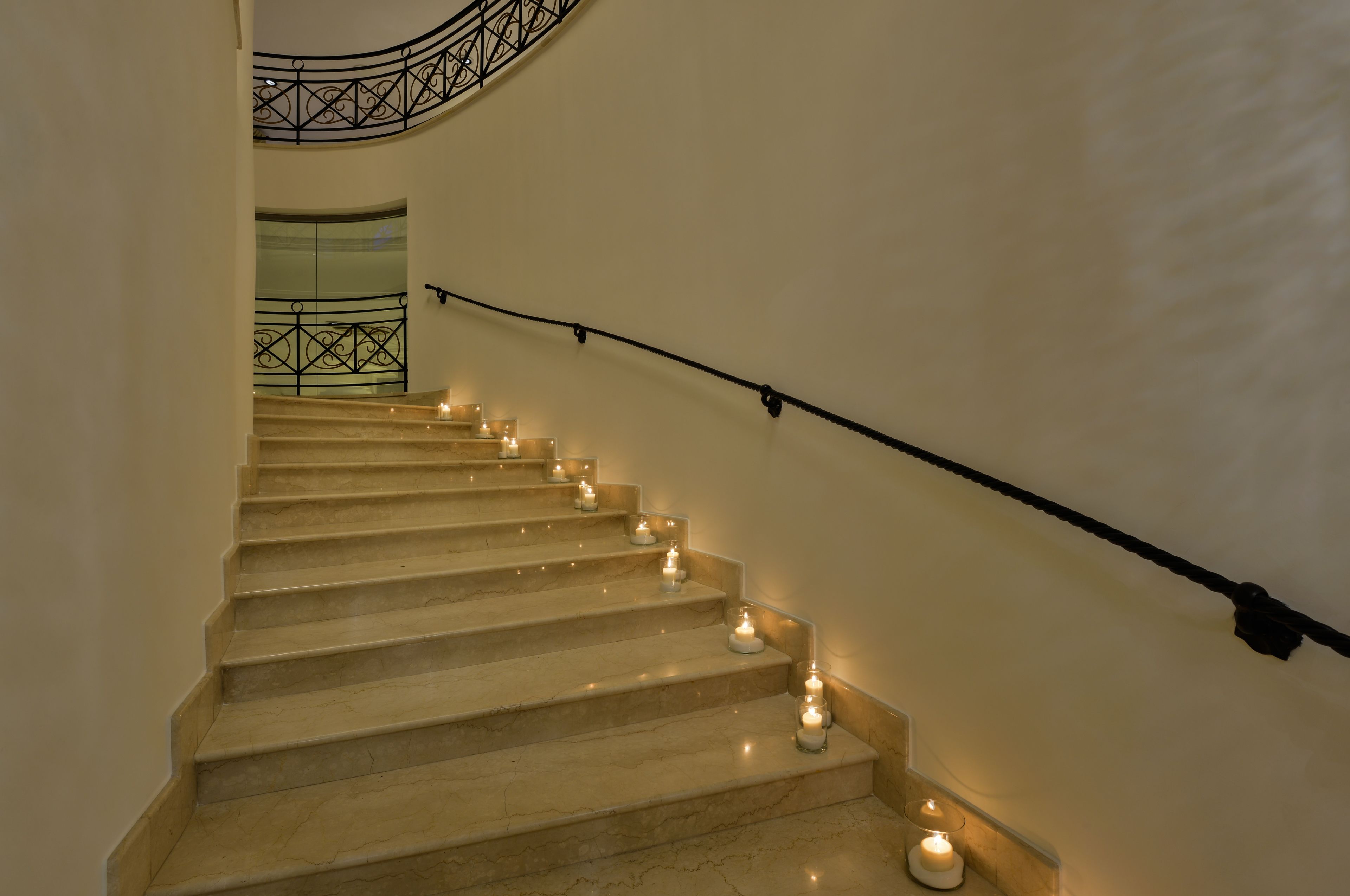 A staircase with marble steps and black handrails, decorated with lit candles.