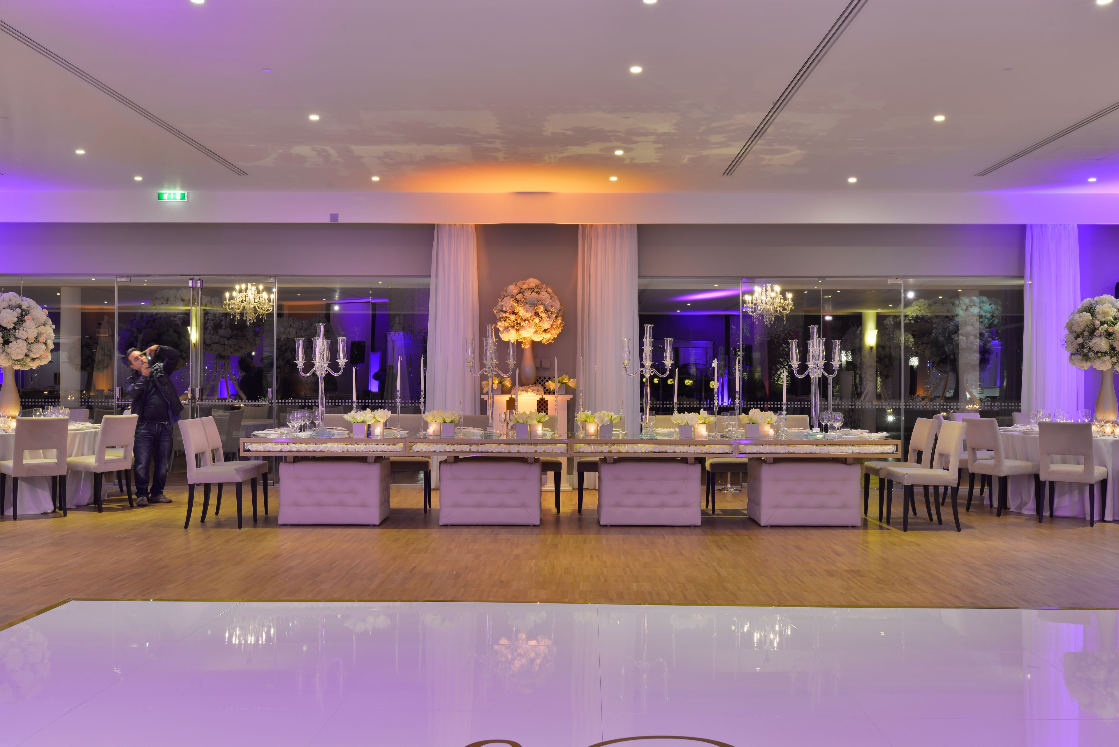 A banquet hall with long tables, chairs, and chandeliers.
