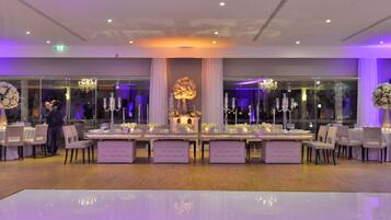 A banquet hall with long tables, chairs, and chandeliers.