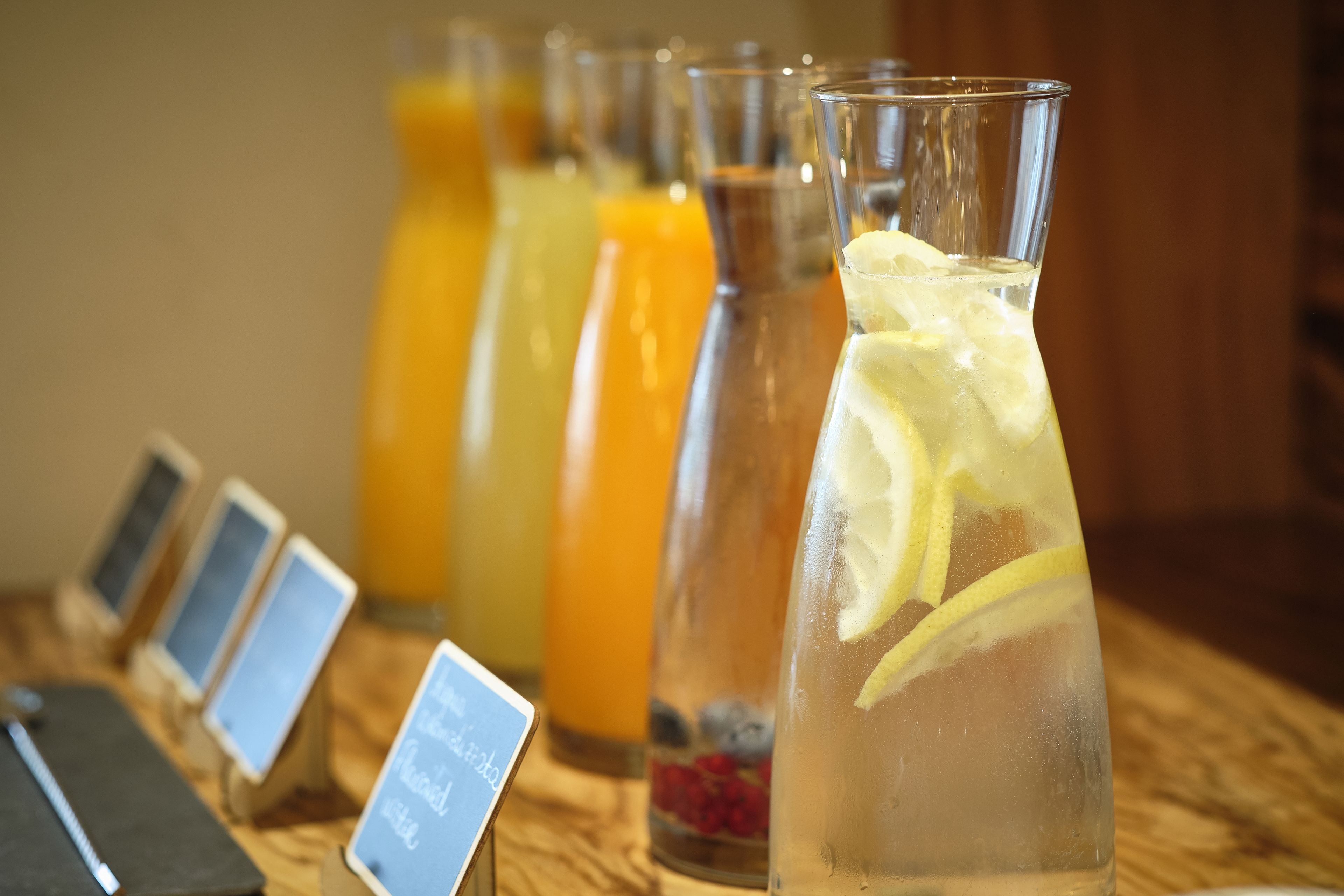 Une sélection de boissons servies dans des récipients en verre, notamment une carafe contenant des tranches de citron et une bouteille remplie de fruits rouges.