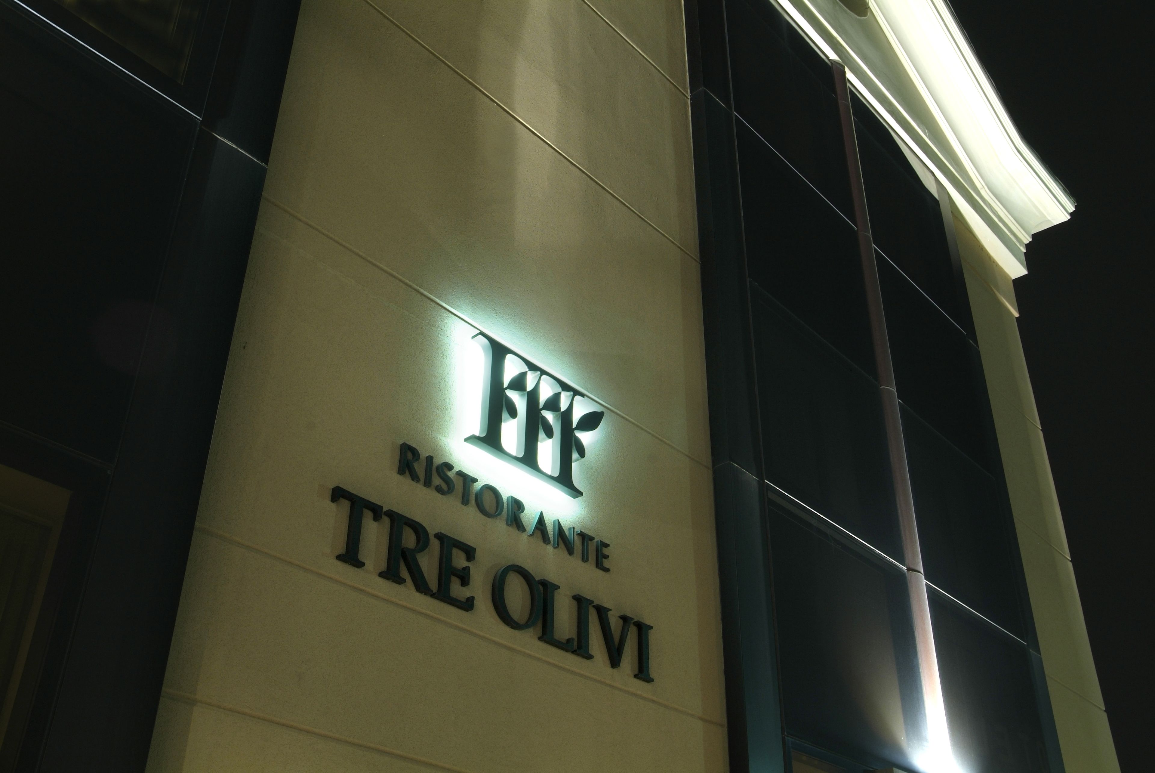 A building with a sign reading "Ristorante TRE OLVI" illuminated at night.