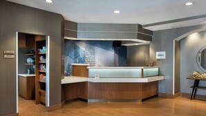 A reception area with a wooden reception desk, a wall-mounted TV, and a sign for 'The Market'. - Springhill Suites By Marriott - Danbury (Danbury)