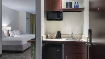 Een hotelkamer met een bed, een kitchenette met een magnetron, koffiezetapparaat en minibar.