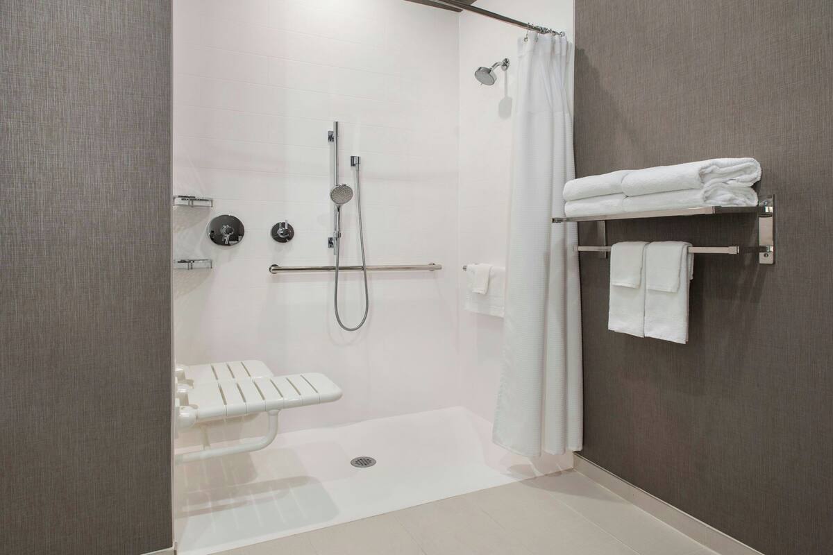 A modern bathroom with a walk-in shower, a toilet, and a towel rack.