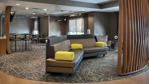 A modern hotel lobby with a sectional sofa, bar area, and a large window providing natural light. - Springhill Suites By Marriott - Danbury (Danbury)