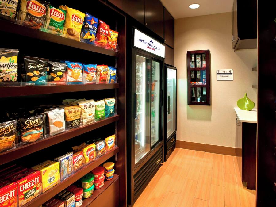 A snack aisle in a hotel with various packaged snacks and a refrigerated display.
