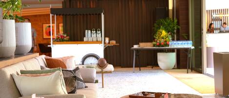 A modern living room with a sofa, coffee table, and decorative items. There is a kitchen area in the background with a counter and various kitchen items.