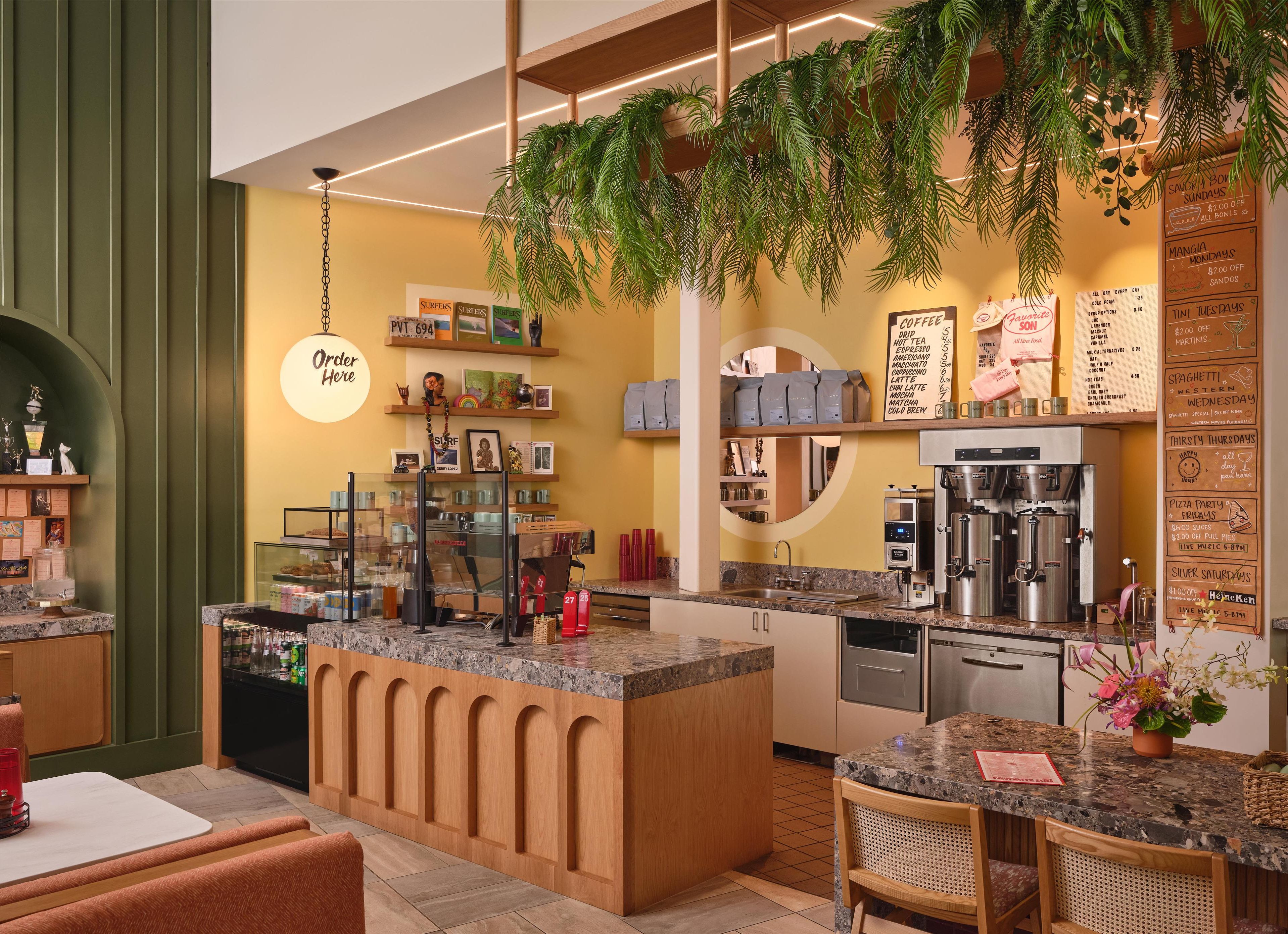Un café chaleureux avec un îlot central, des machines à café et un tableau affichant le menu.