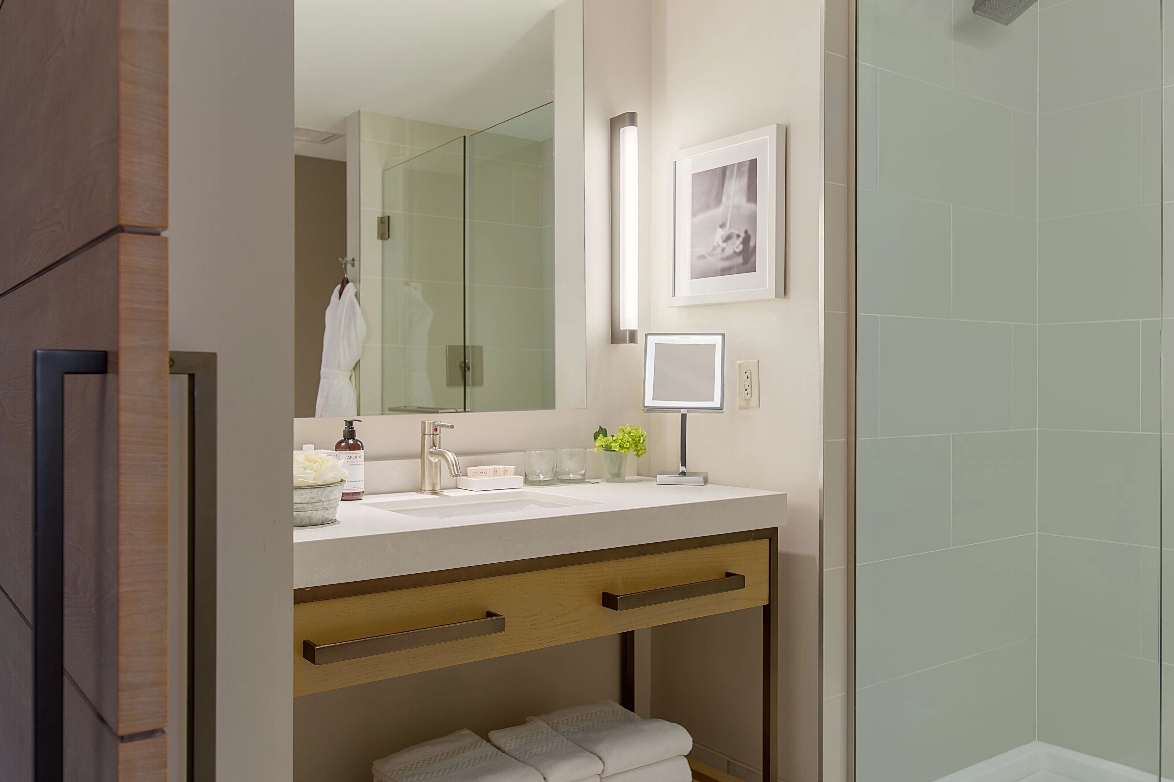 A modern bathroom with a glass shower enclosure, a vanity with a mirror, and a towel rack.