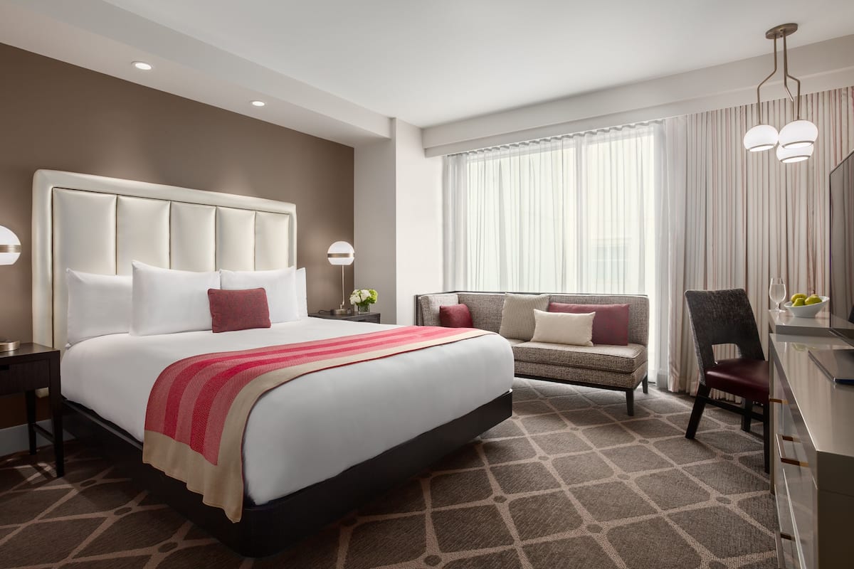 Una habitación de hotel con una cama grande, un sofá, un escritorio y una silla.