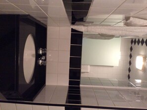 A bathroom with a large bathtub, a mirror, and a tiled wall. - Park Savoy (New York)