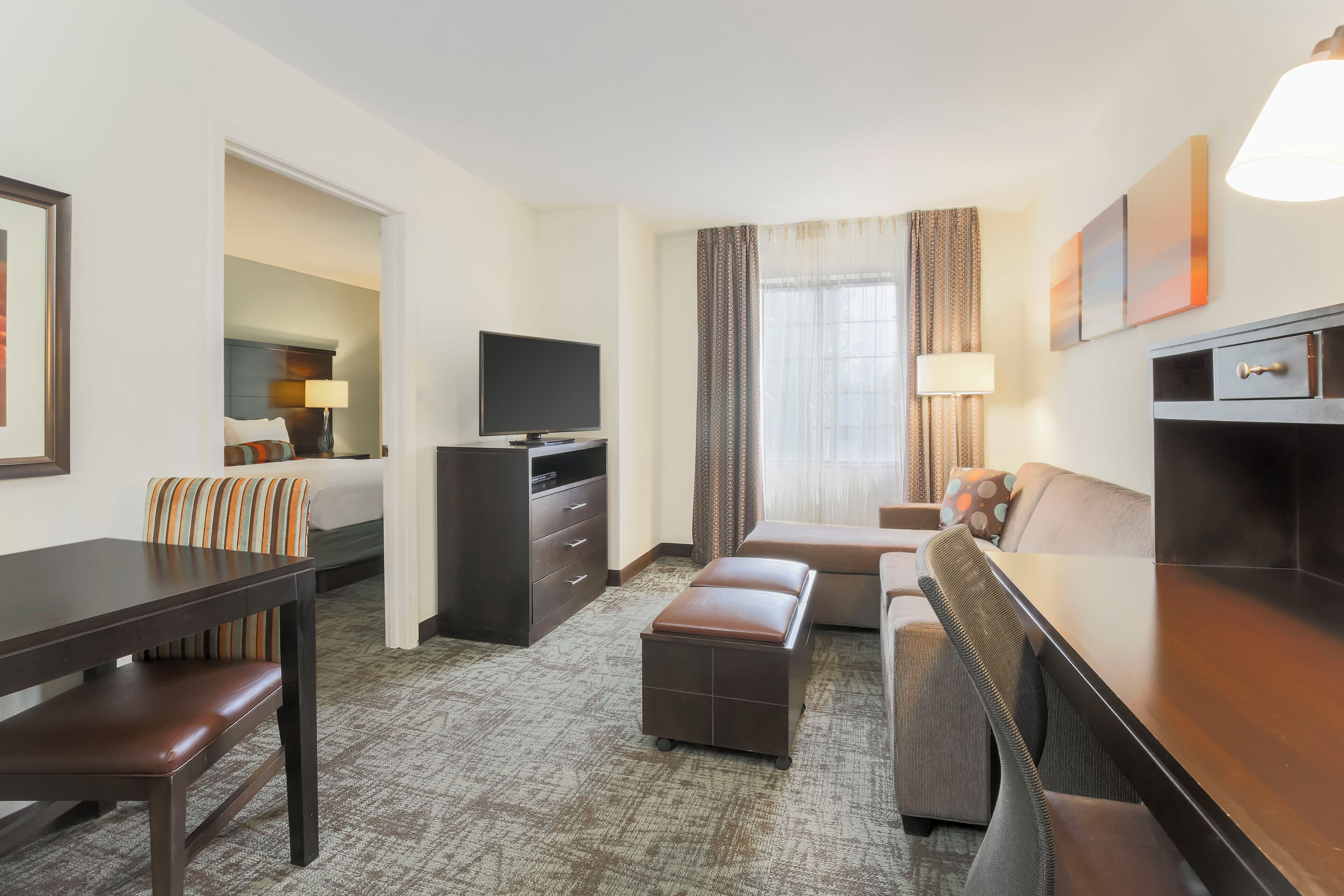 A hotel room with a bed, a desk, a television, a sofa, and a dining table.