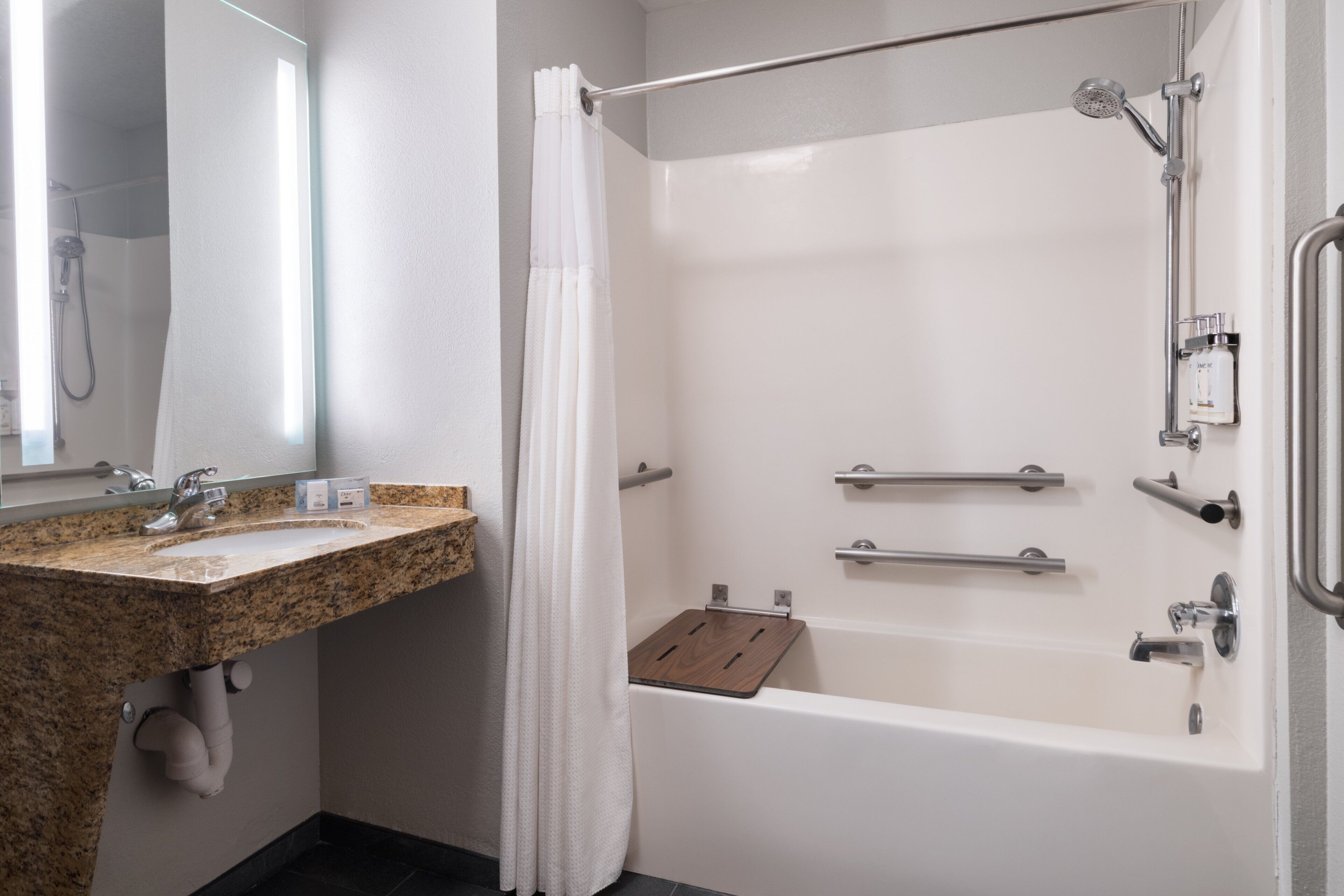 Un baño moderno con lavamanos de granito, una bañera blanca y una ducha con puerta de cristal.