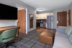 A compact living space with a kitchenette, a flat-screen TV mounted on the wall, a dining area with a table and chairs, and a sofa with a cushion. - Staybridge Suites Columbus-Dublin by IHG (Dublin)