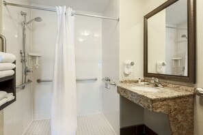 A bathroom with a shower, grab bars, a sink, and a mirror. - Staybridge Suites Columbus-Dublin by IHG (Dublin)