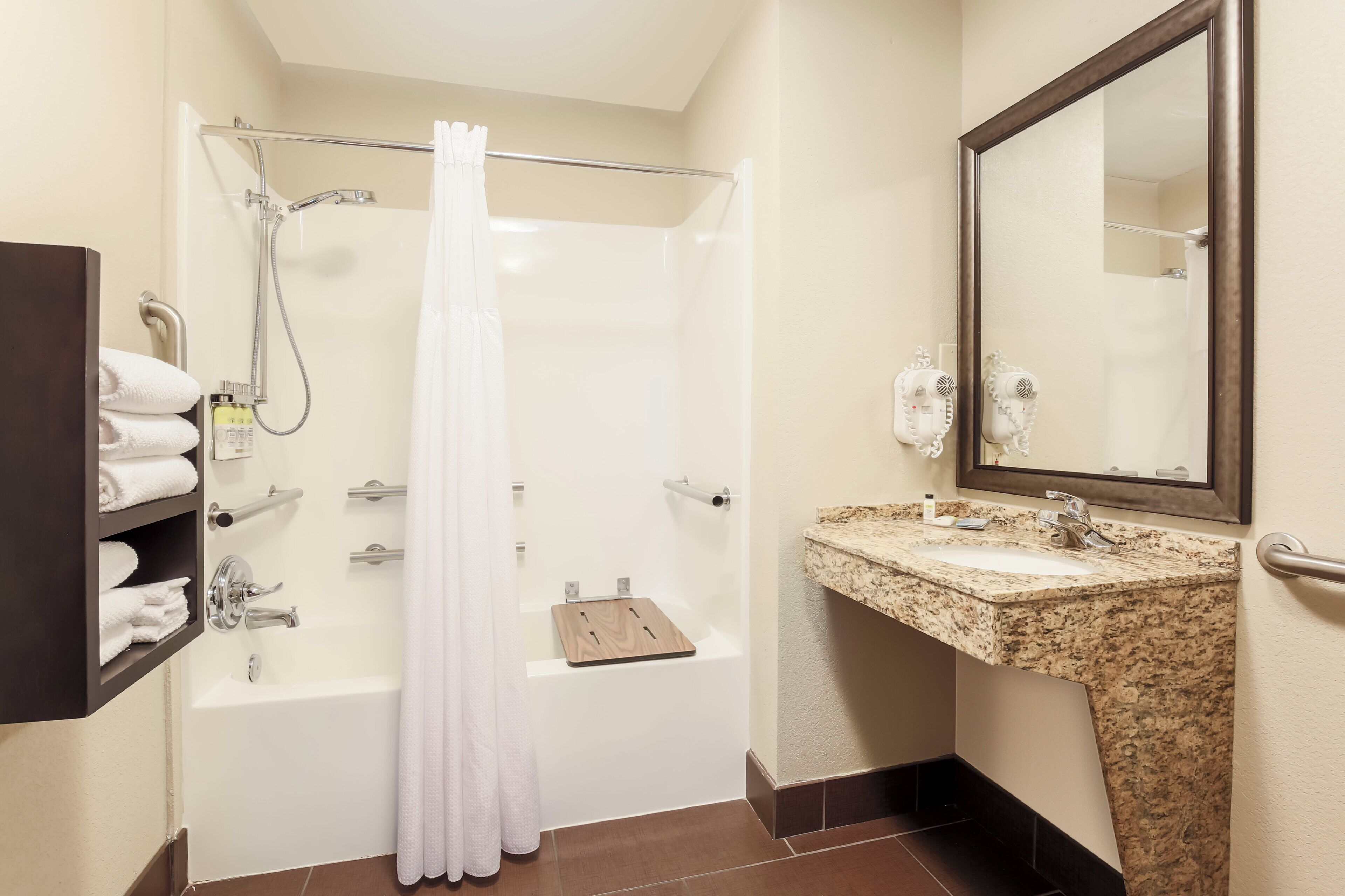 A bathroom with a bathtub, shower, and a vanity with a mirror.