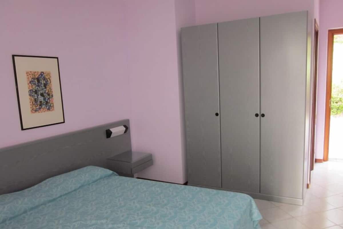 Une chambre à coucher avec un lit, une armoire et un tableau encadré au mur.