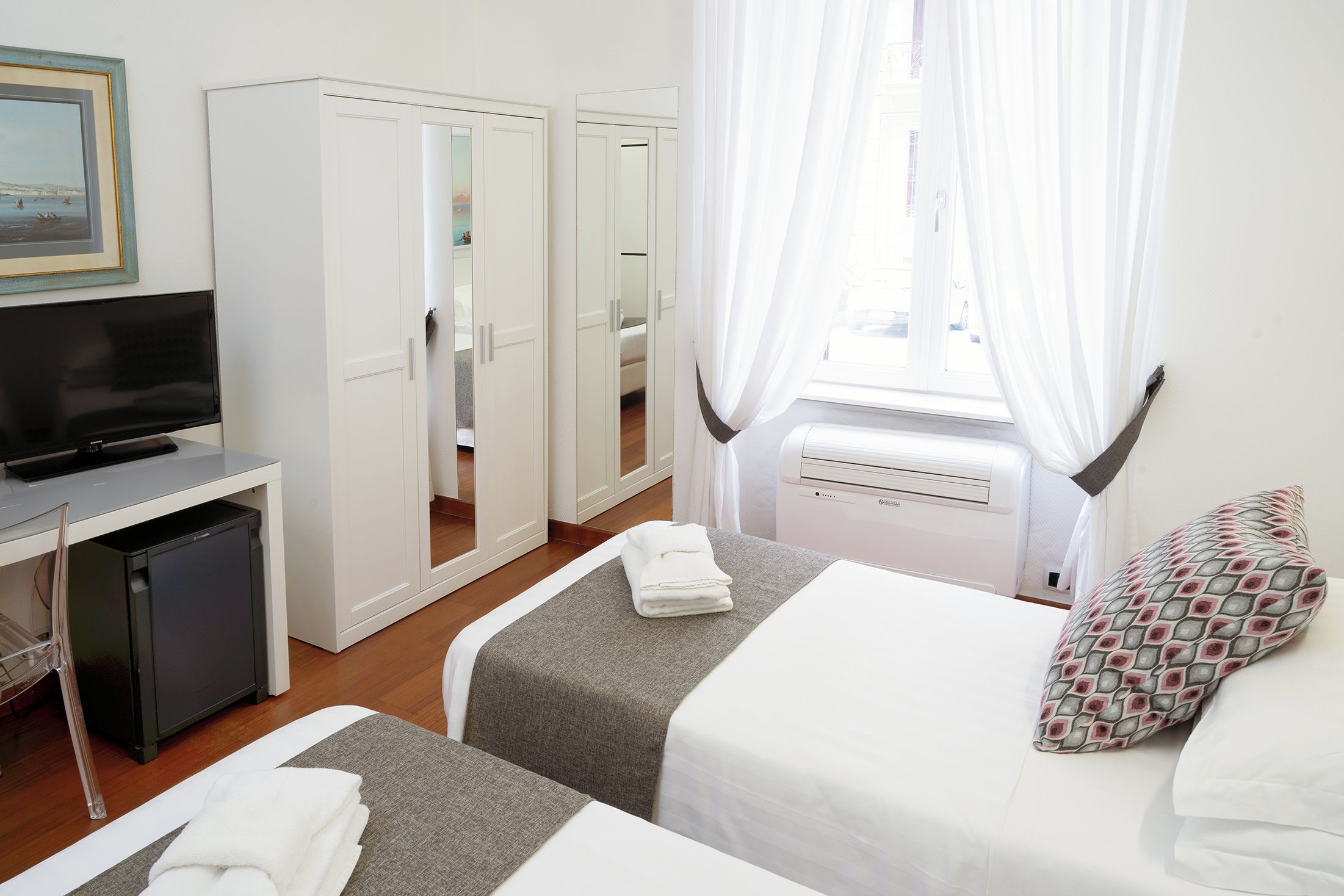 A hotel room with a bed, a TV, a desk, and a wardrobe.