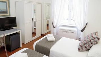 Een hotelkamer met een bed, een televisie, een bureau en een kledingkast.