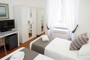 A hotel room with a bed, a TV, a desk, and a wardrobe. - Rex Lifestyle Hotel (Naples)