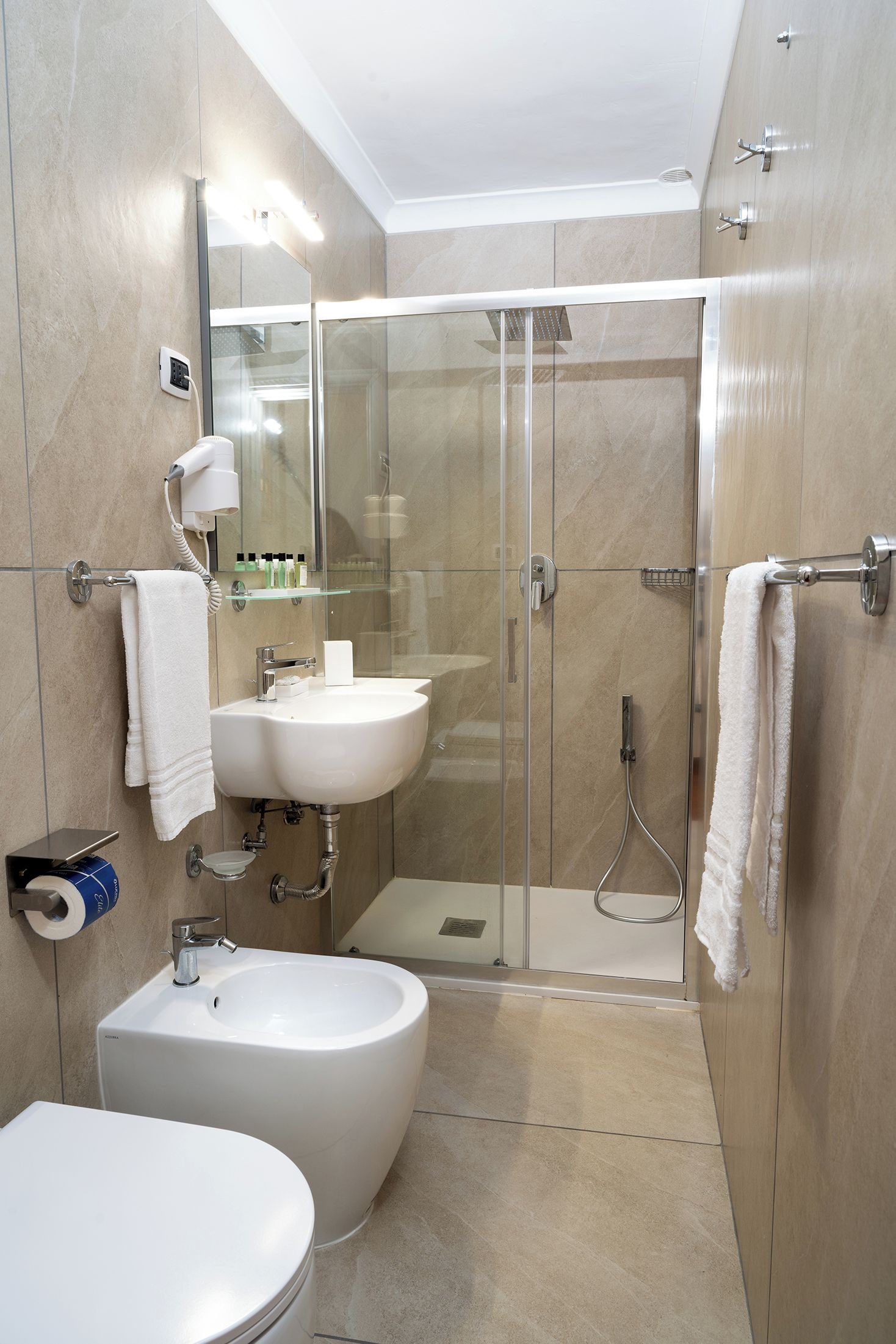 Un bagno moderno con doccia vetro, due lavabi, un bidet e un water.