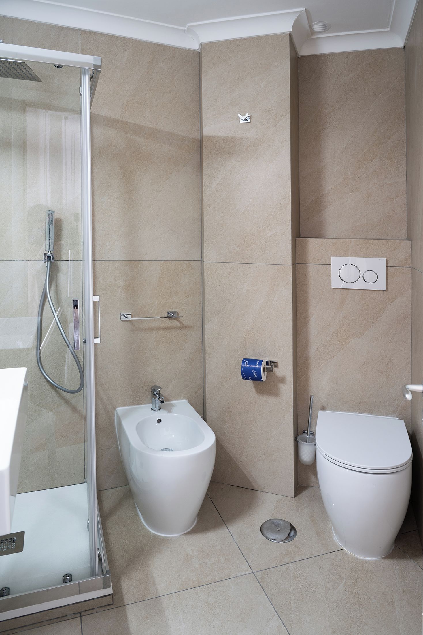 A modern bathroom with a glass-enclosed shower, a bidet, and a toilet.