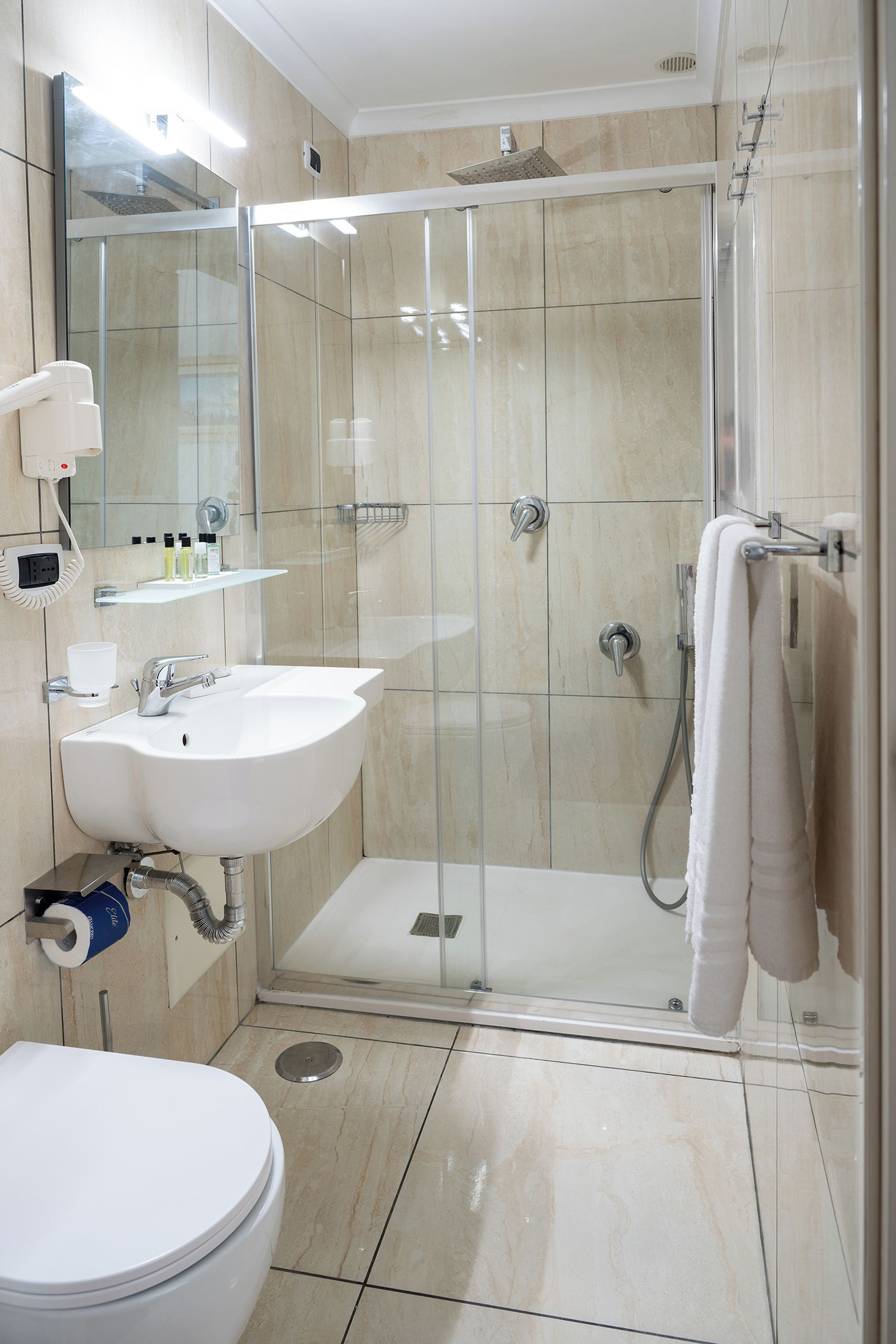 A modern bathroom with a glass-enclosed shower, a white sink, and a toilet.