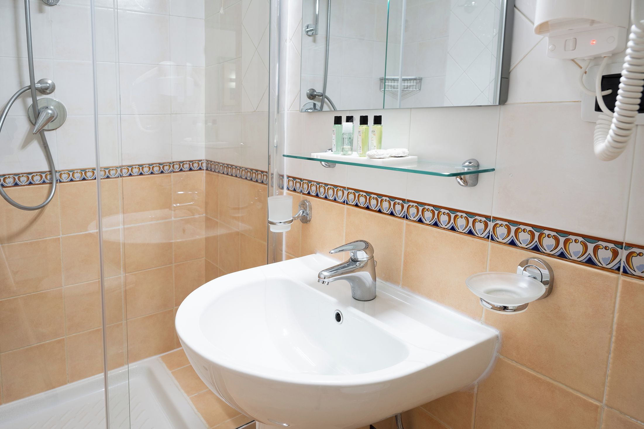 A bathroom with a white sink, a glass shower enclosure, and a mirror above the sink.