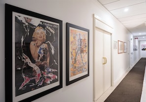 A hallway with framed artworks on the walls and a door with a golden handle. - Rex Lifestyle Hotel (Naples)