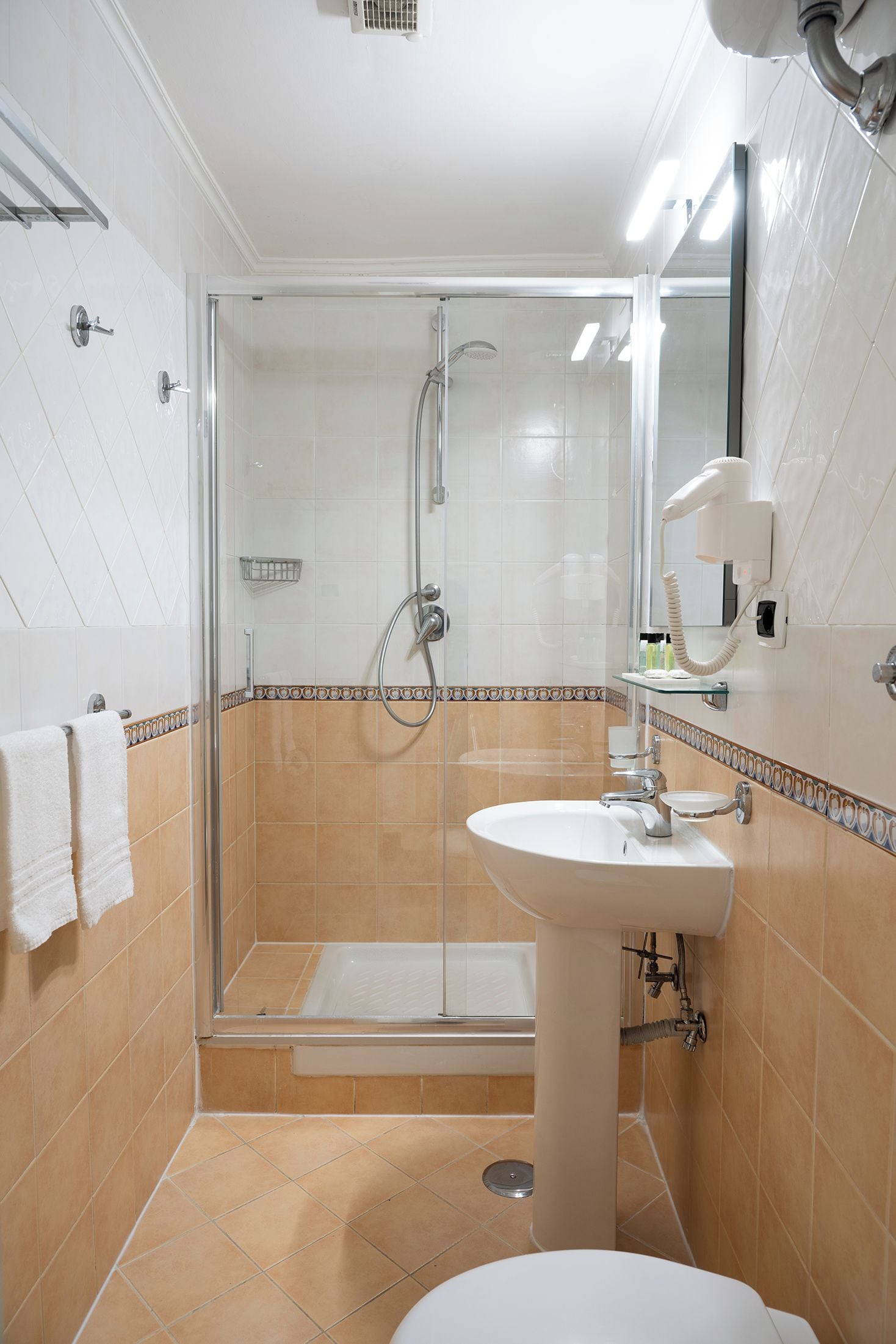 Ein Badezimmer mit einer Duschkabine, einem weißen Waschbecken und einer Toilette.