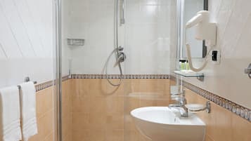 Ein Badezimmer mit einer Duschkabine, einem weißen Waschbecken und einer Toilette.