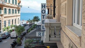 Un hotel con vistas al mar, mobiliario exterior y una mesa de mármol en primer plano.