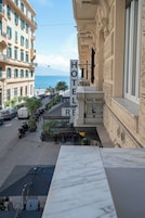 A hotel with a view of the sea, outdoor seating, and a marble table in the foreground.