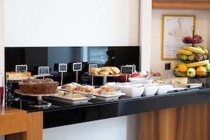 A buffet counter with various food items and labels. - Rex Lifestyle Hotel (Naples)