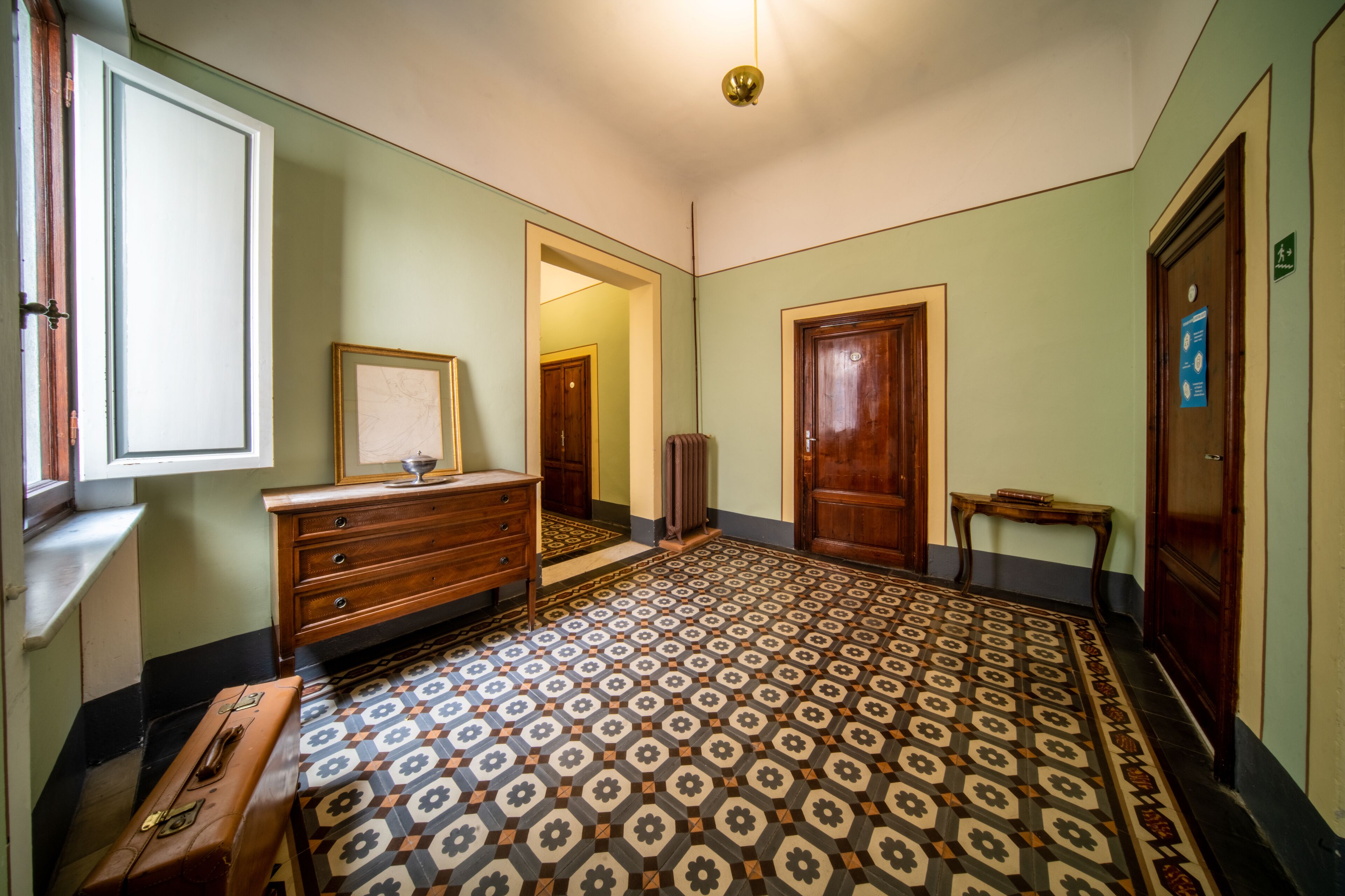 A room with a patterned floor, wooden furniture, and a door with a sign.