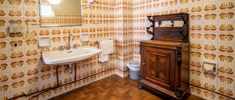 Un baño con baldosas estampadas, un lavamanos, un espejo y un mueble de madera.