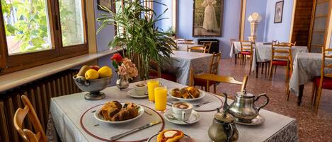 Un comedor con una mesa dispuesta para el desayuno, que incluye pan, jamón y una tetera.