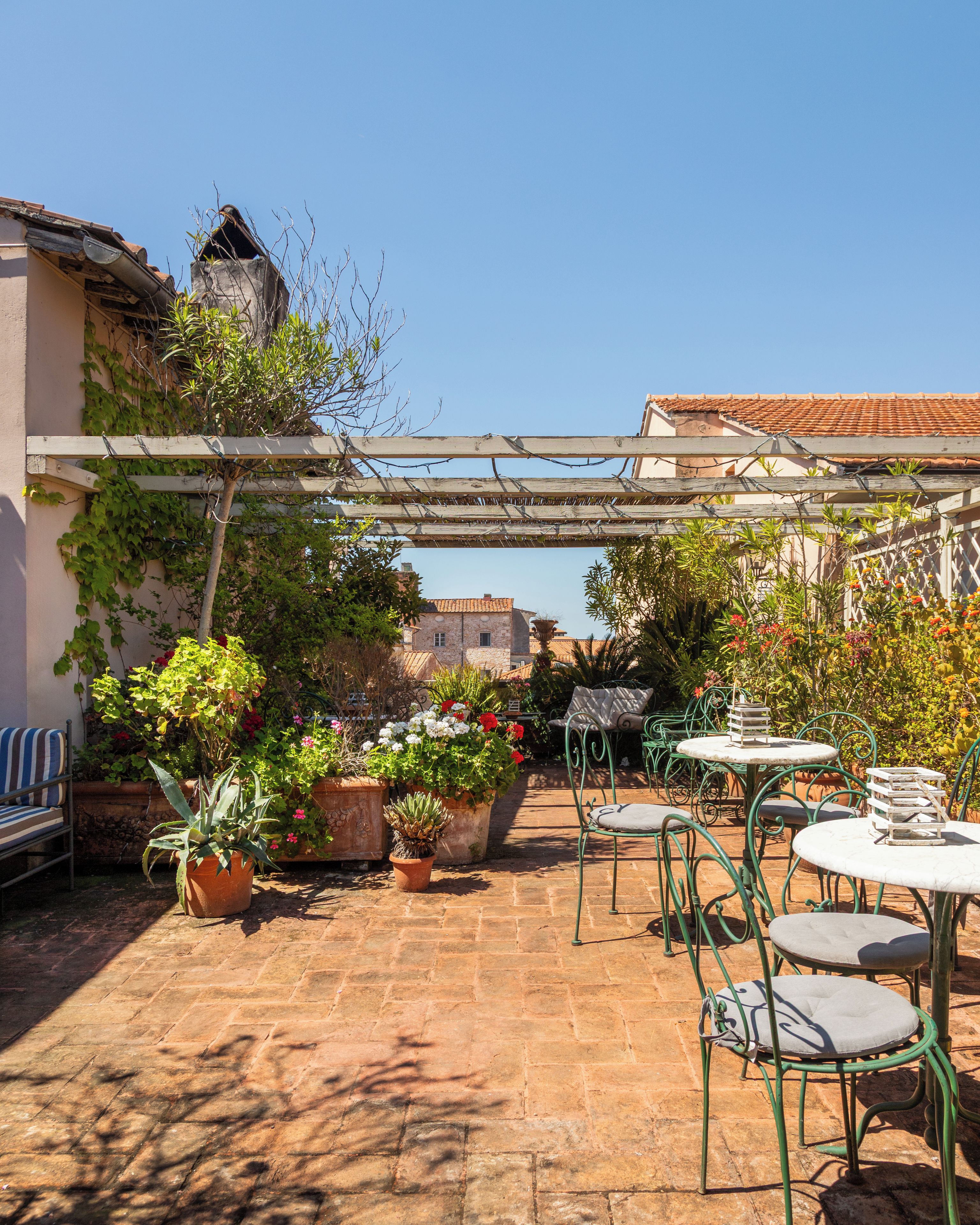 Un espace patio aménagé avec des meubles d’extérieur, des plantes en pot et une vue sur les bâtiments en arrière-plan.